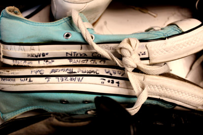The other shoes surrounded the blue ones are black and white making the blue the only colour in the photo so it stands out more. However the black shoe at the bottom is obstructing the view of the lower blue shoe and it would look better if it was moved out of the way more. Also the main focus of the image is the writing on the edge of the bottom of the blue shoes. Some of the writing cannot be seen very well though. This may be through poor focus of the image or just deuteriation of the marker on the shoe due to age. 